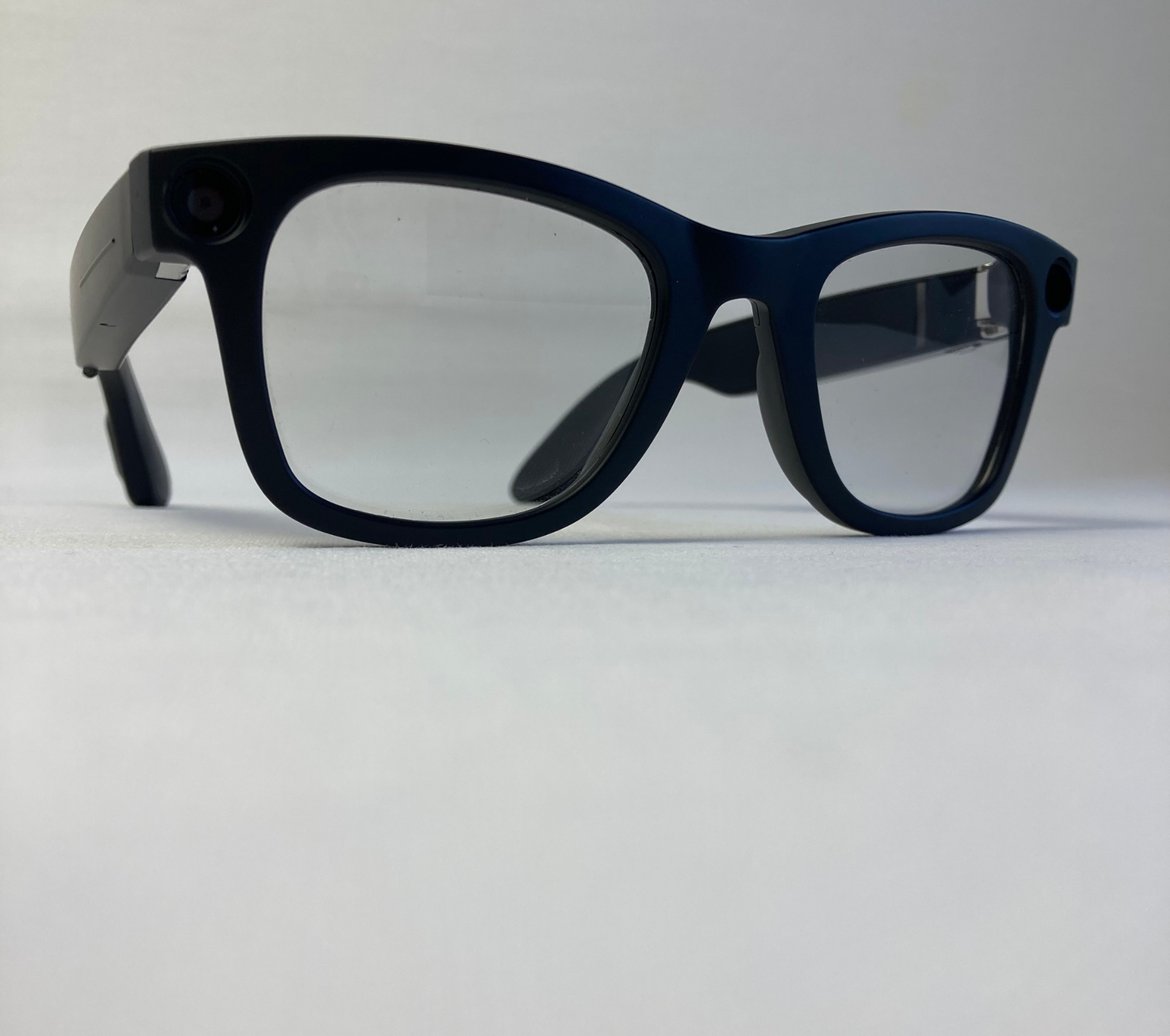 Lunettes caméra 4K noires avec objectif intégré dans la monture, design discret, photographiées sur fond blanc pour présentation produit.